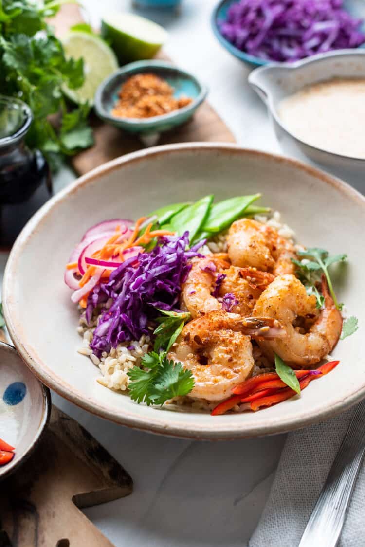 Thai-style Shrimp Bowls with brown rice, red cabbage, red onions, carrots, and snow peas served with Spicy Coconut Dressing on the side.