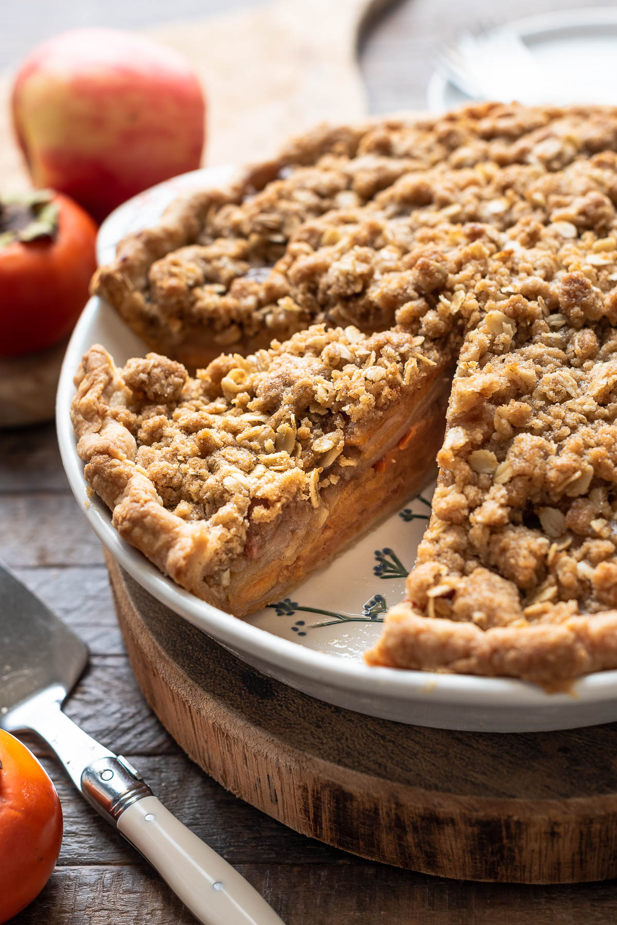 Sliced Persimmon Apple Crumb Pie in a white pie plate.