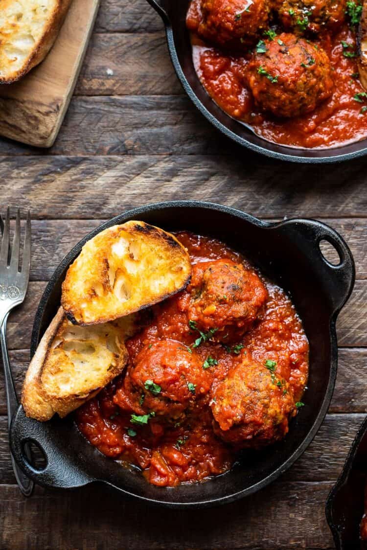 A black dish filled with marinara sauce, meatless mushroom meatballs, and two slices of Texas toast.