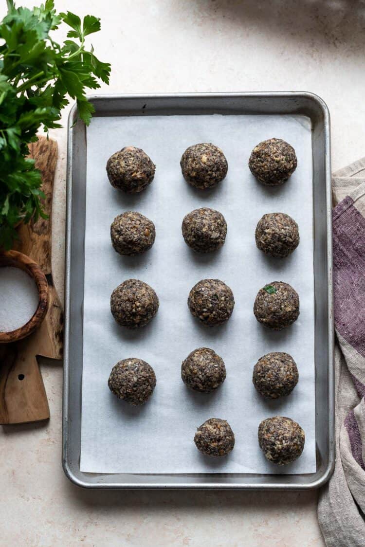 Mushroom meatballs on a baking sheet prepped and ready to be cooked.