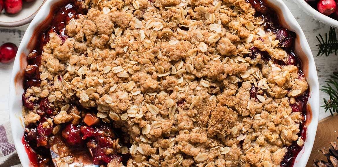 Cranberry Apple Crisp in a white baking dish with a spoon.