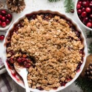 Cranberry Apple Crisp in a white baking dish with a spoon.