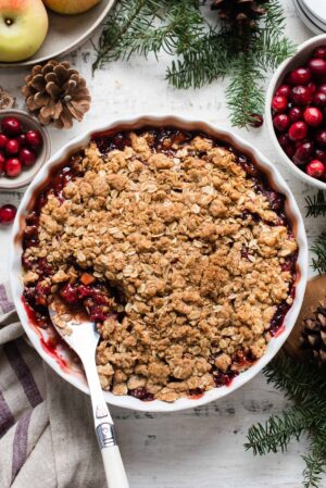 Cranberry Apple Crisp in a white baking dish with a spoon.