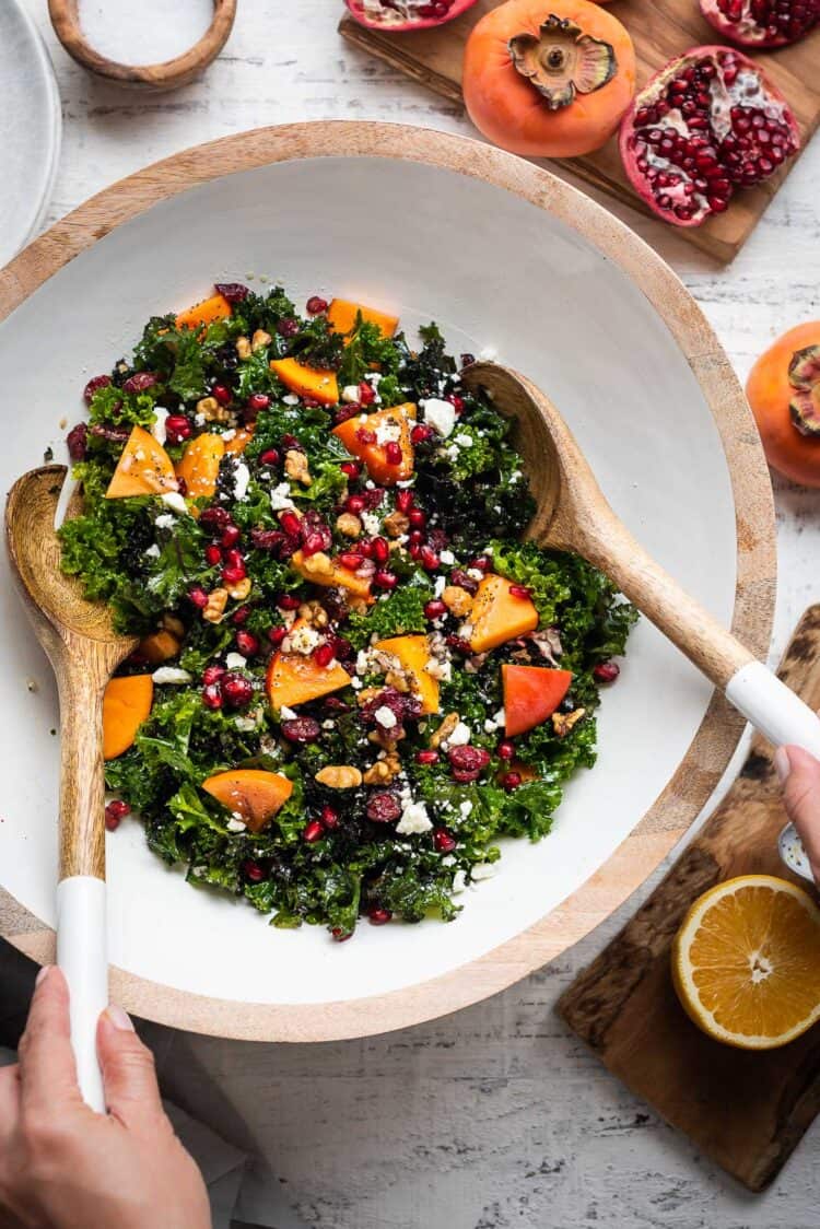 Tossing Kale Persimmon Salad in a salad bowl