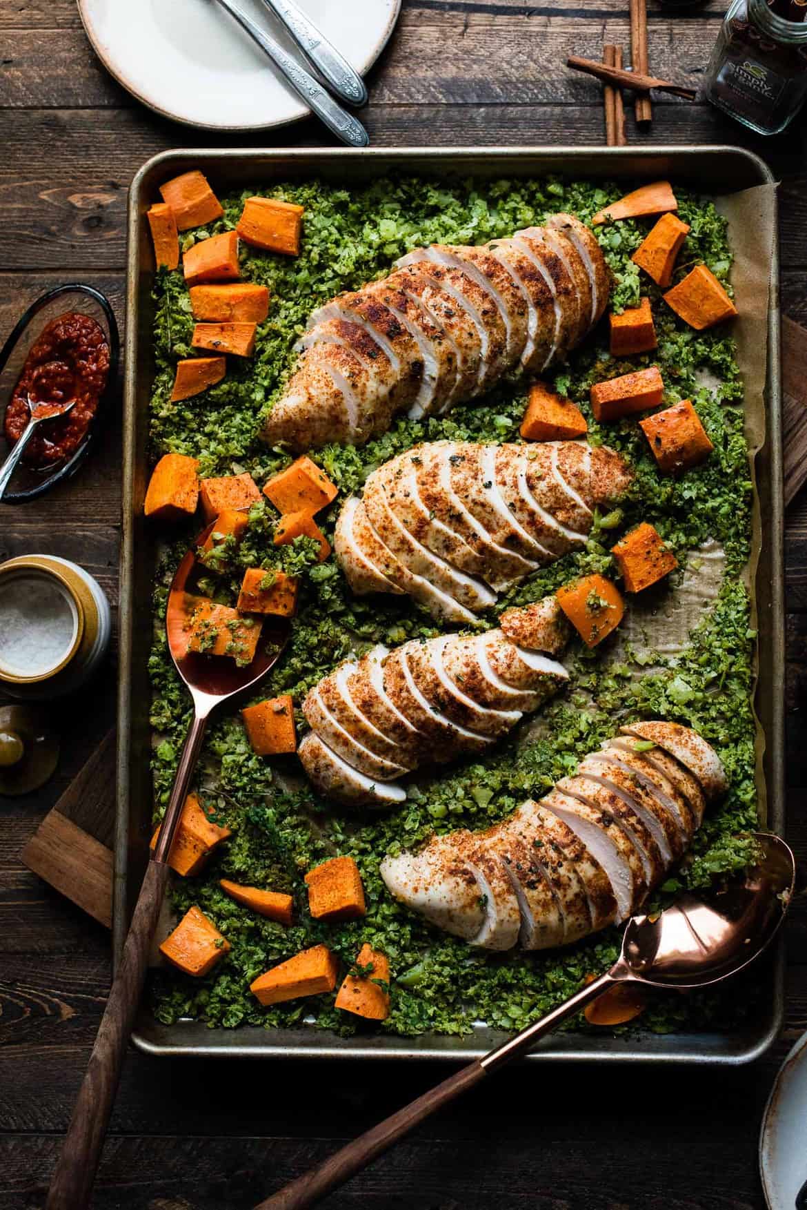 Sliced Sheet Pan Moroccan Chicken with Broccoli Rice and Sweet Potatoes on a baking tray.