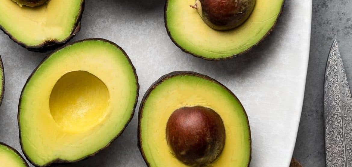 Avocados halved on a platter and tips on how to freeze avocados.