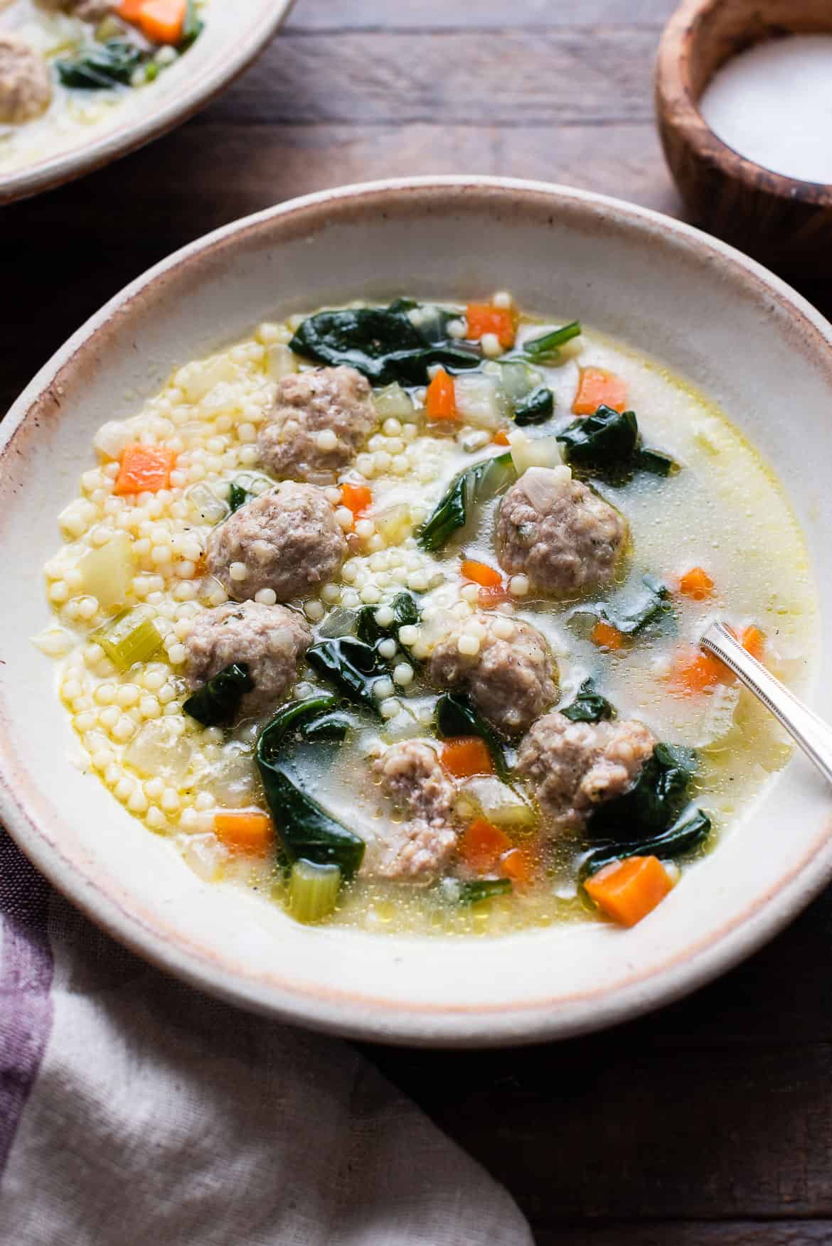 A bowl of homemade Italian Wedding Soup with meatballs, carrots, celery, and spinach.