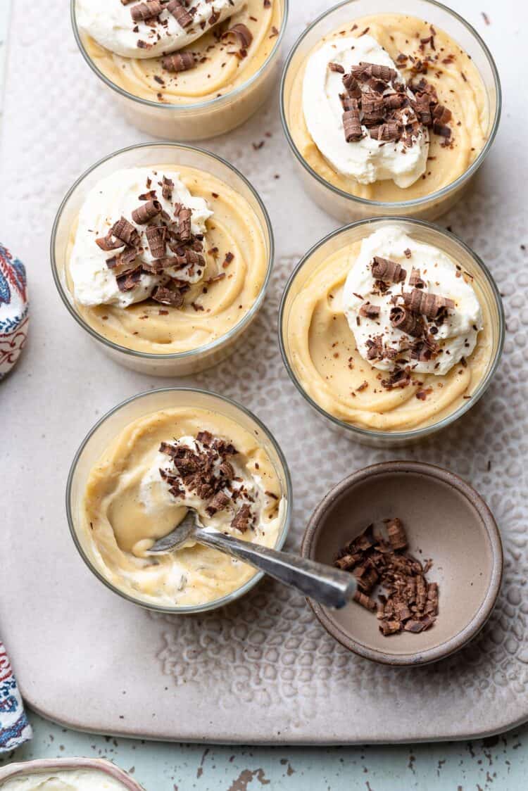 Cognac Butterscotch Pudding in glass cups topped with whipped cream and chocolate shavings.