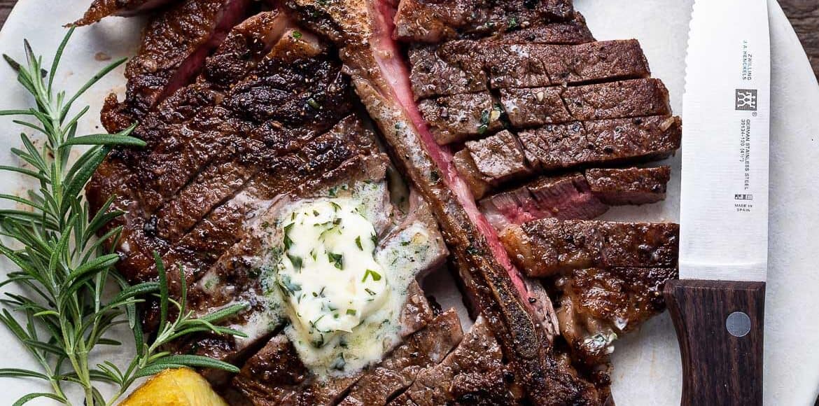 Angus Beef Steak Recipe with Garlic Herb Compound Butter, with potatoes and rosemary garnish on a plate.