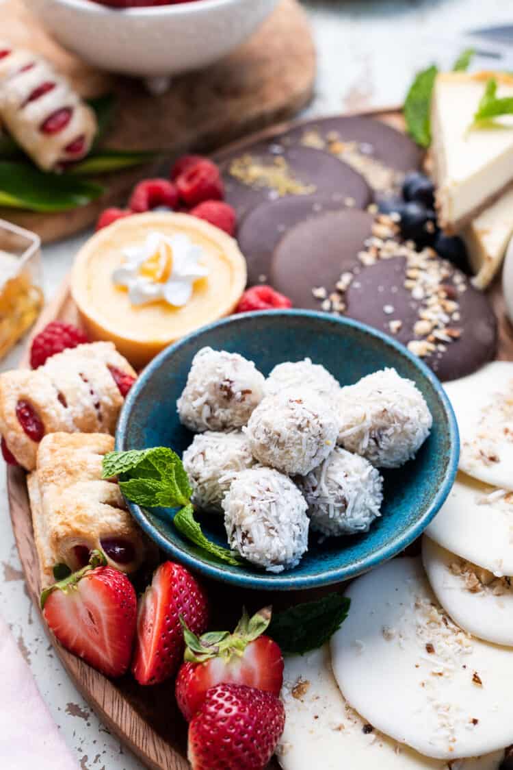 Coconut truffles on a Simple Dessert Charcuterie Board with fruit, cookies, cake, cheesecake, candied apples, and more!