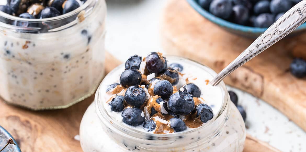 Blueberry Muffin Overnight Oats with fresh blueberries, almond butter and coconut flakes in a jar.