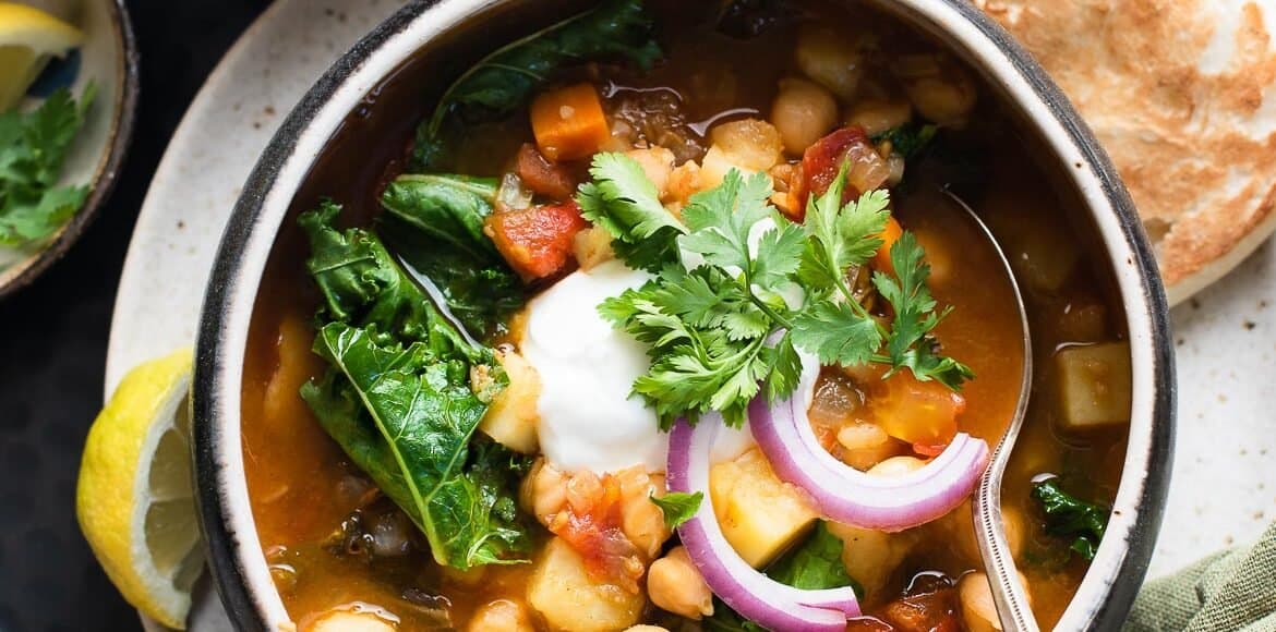 Chana Masala Soup in a soup bowl topped with cilantro, red onion, and greek yogurt.