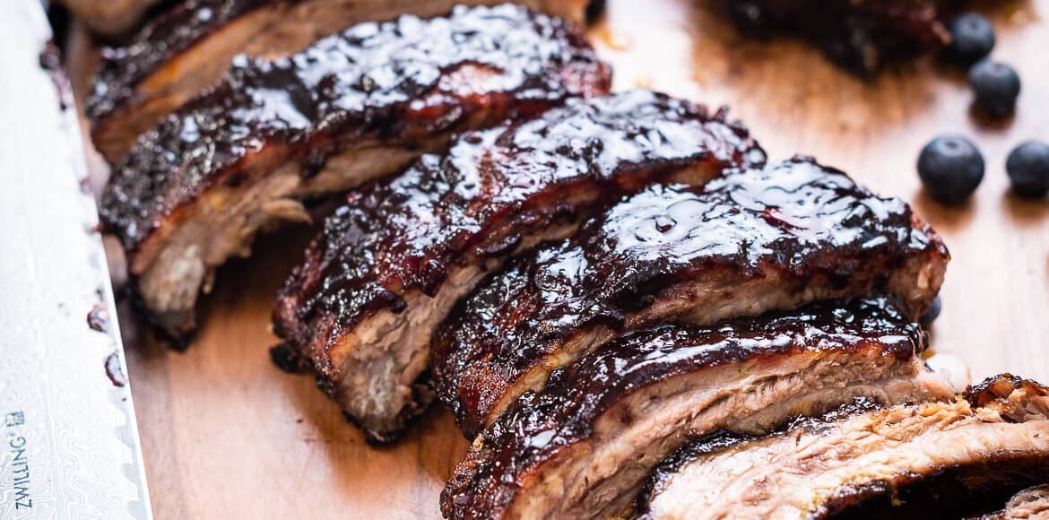 Baby Back Ribs with Blueberry Balsamic Barbecue Sauce sliced on a wooden tray.