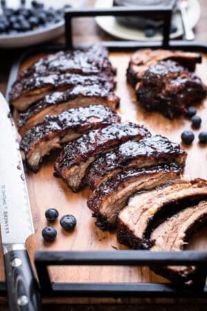 Baby Back Ribs with Blueberry Balsamic Barbecue Sauce sliced on a wooden tray.