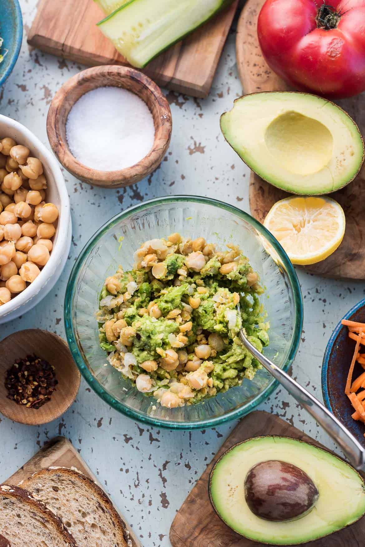 Smashed avocados and chickpeas in a clear bowl.