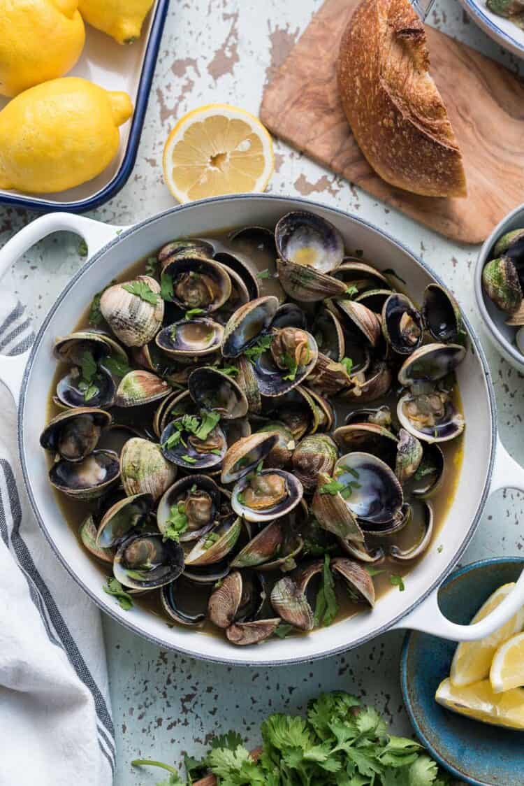 Steamed clams in broth without wine in a white pot.