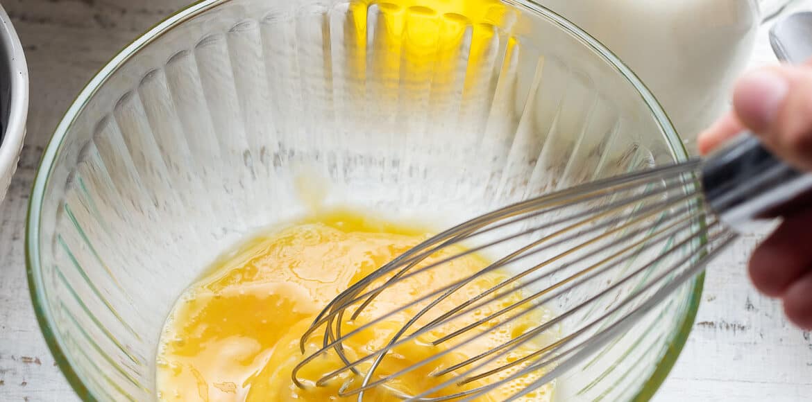 Whipping eggs in a ribbed glass bowl.