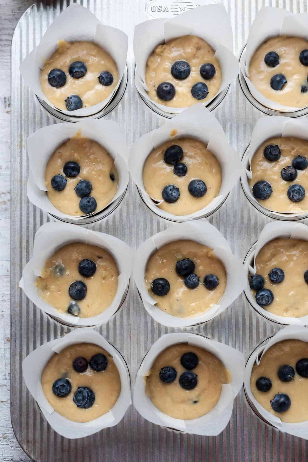 Batter with blueberries in a muffin pan.