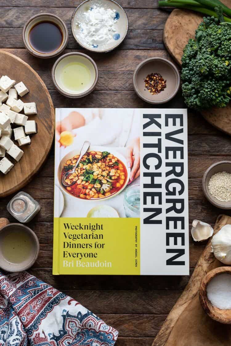 Evergreen Kitchen Cookbook on table with ingredients for Firecracker Tofu and Broccolini recipe.