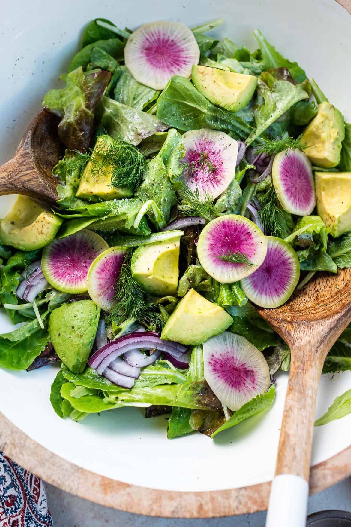 Lettuce Salad with Mayonnaise Dressing, watermelon radishes, avocados, red onion, and dill in a large salad bowl.