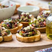 Olive Bruschetta on a wood serving board.