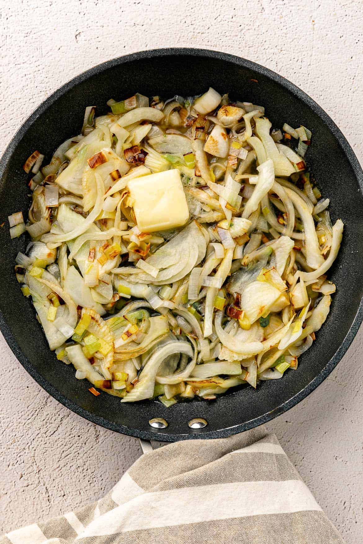 Adding butter to braised fennel and leeks.