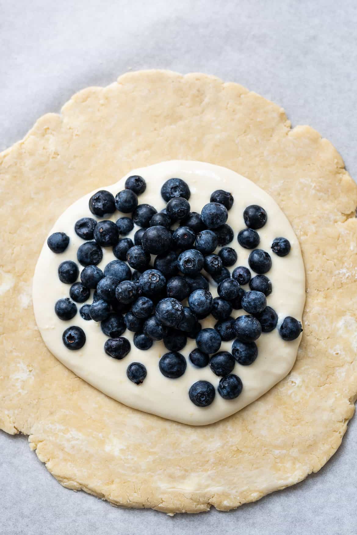 Yogurt cream and blueberry topped pastry dough for a galette.