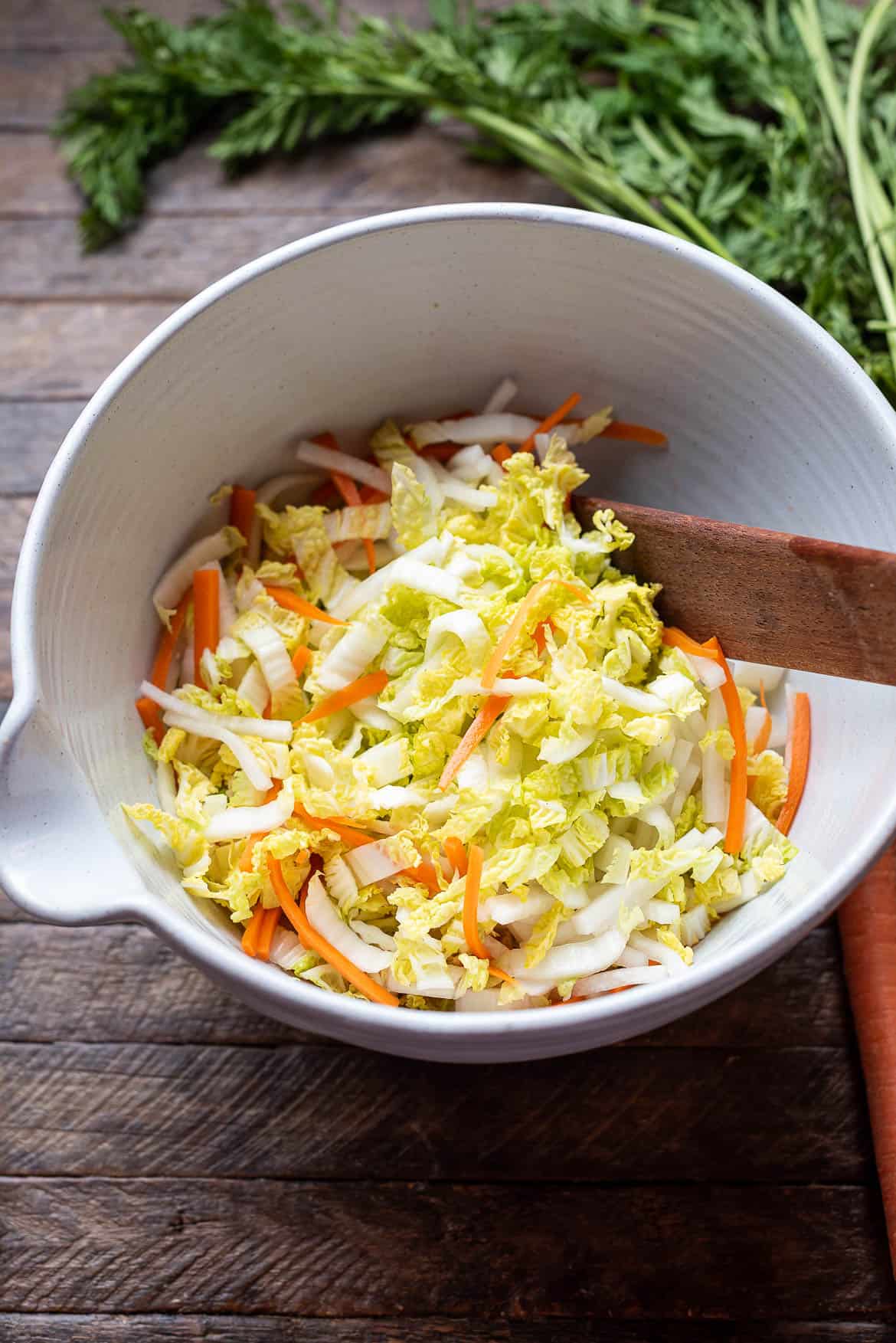 Shredded napa cabbage and carrots in a mixing bowl.