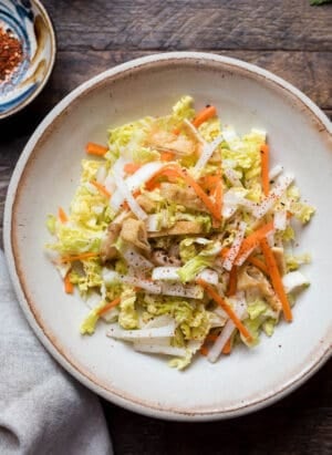 Quick Pickled Napa Cabbage with carrot and daikon in a bowl on a wood table.