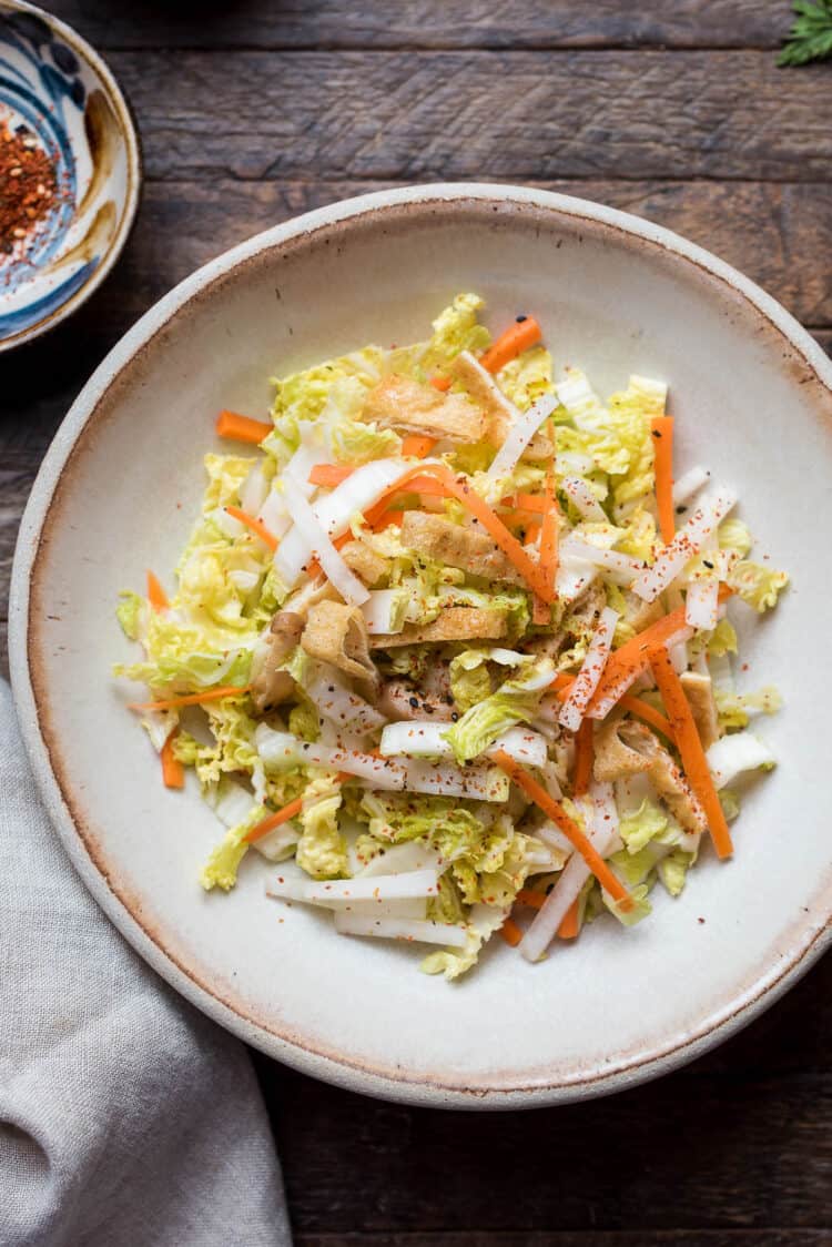 Quick Pickled Napa Cabbage with carrot and daikon in a bowl on a wood table.