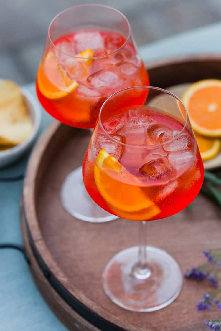 Aperol Spritz in wine glasses with ice, garnished with orange slices.