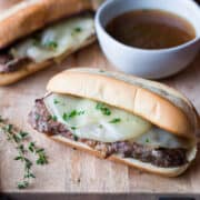 Slow Cooker French Dip Sandwich with Au Jus on a cutting board.