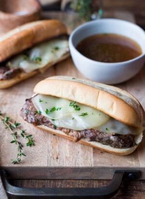 Slow Cooker French Dip Sandwich with Au Jus on a cutting board.