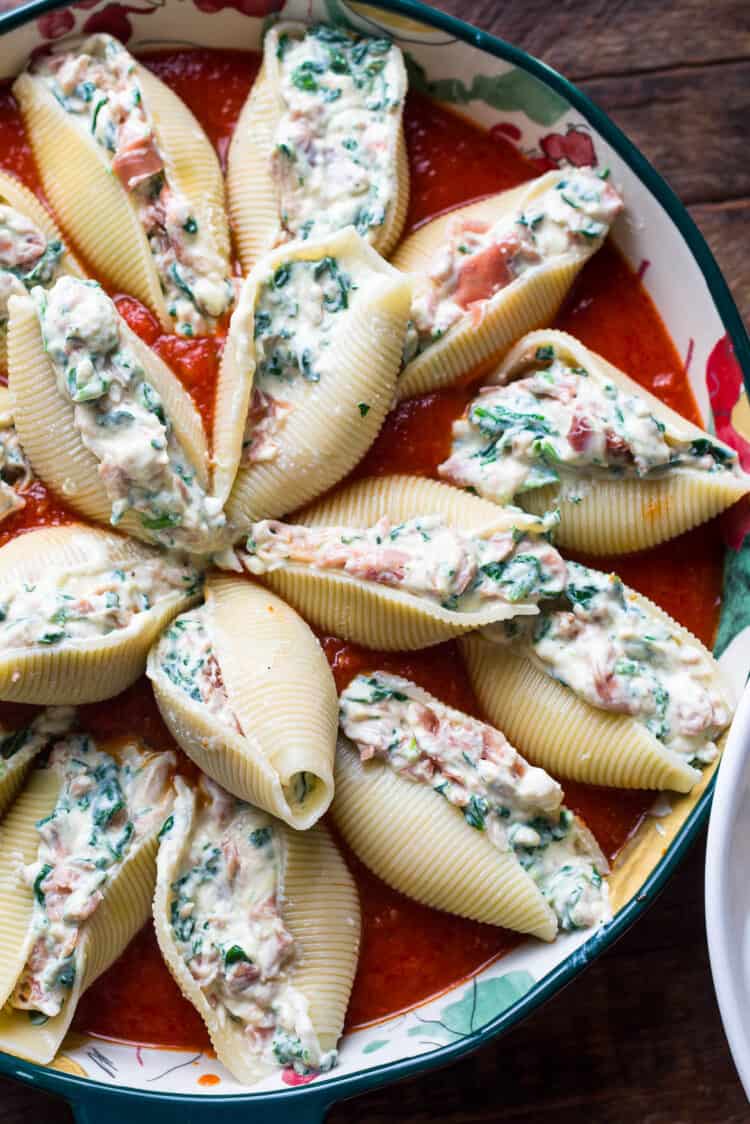 Stuffed shells with prosciutto and spinach ready to bake in a dish.