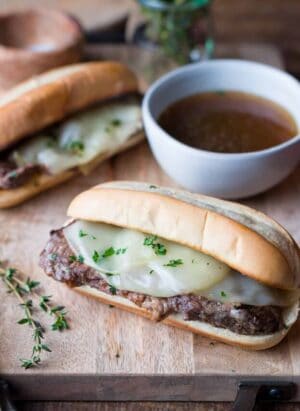 Slow Cooker French Dip Sandwich with Au Jus on a cutting board.