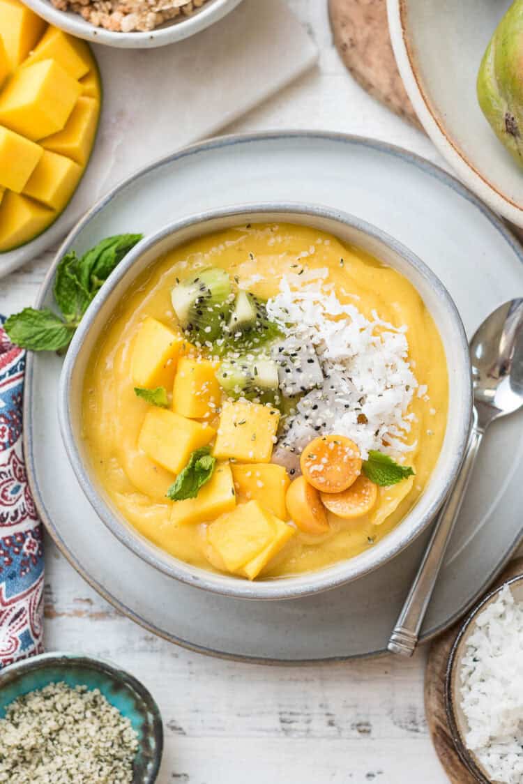 How to Make Tropical Smoothie Bowl with Mango topped with fresh mango, golden berries, and shredded coconut.