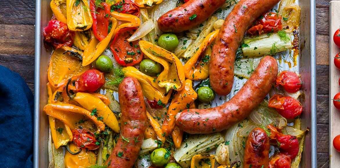 Sheet pan with roasted sausages, peppers, onion, fennel, tomato, and olives.