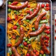 Sheet pan with roasted sausages, peppers, onion, fennel, tomato, and olives.