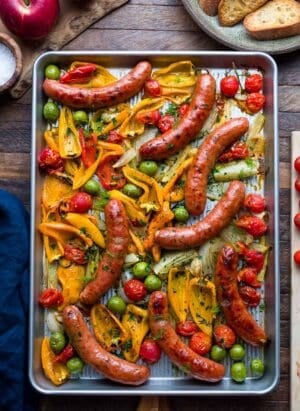 Sheet pan with roasted sausages, peppers, onion, fennel, tomato, and olives.