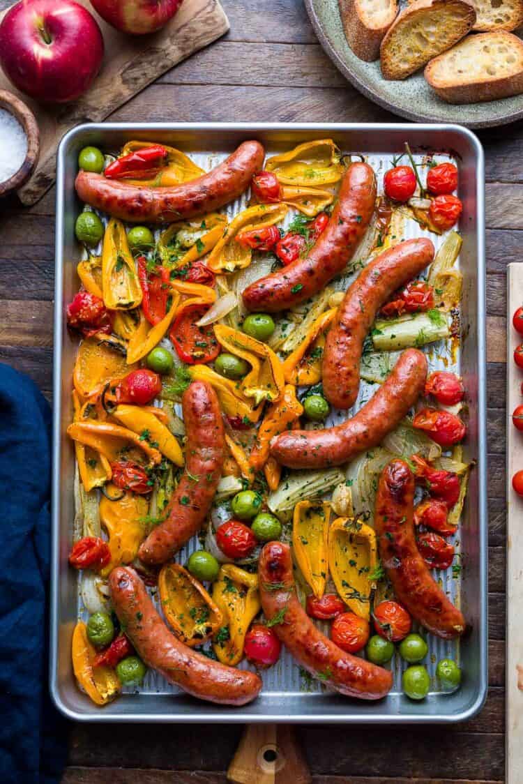 Sheet pan with roasted sausages, peppers, onion, fennel, tomato, and olives.