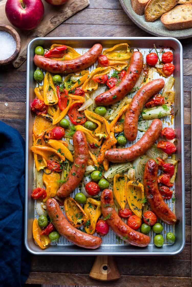 Sheet pan with roasted sausages, peppers, onion, fennel, tomato, and olives.