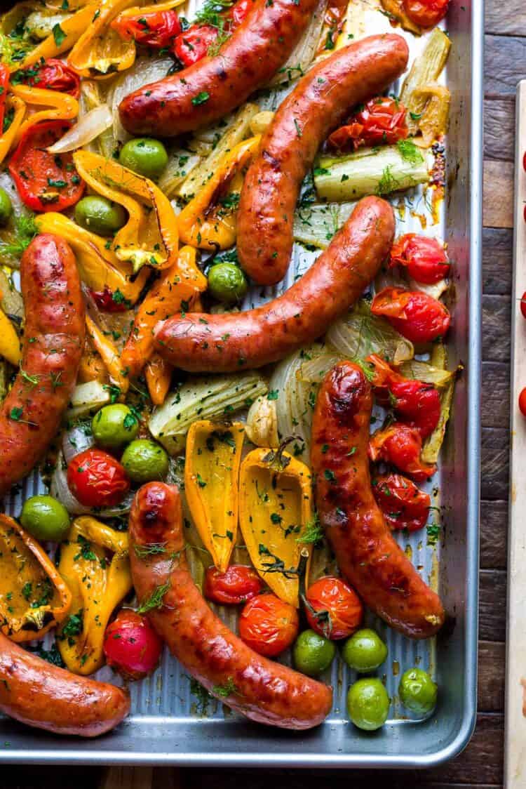 Sheet pan with roasted sausages, peppers, onion, fennel, tomato, and olives.