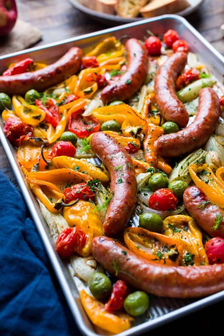 Sheet pan with roasted chicken sausages, peppers, onion, fennel, tomato, and olives.