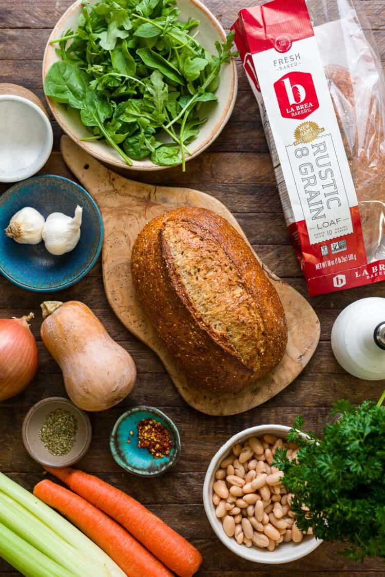 La Brea Bakery Rustic 8 Grain Loaf on a cutting board with ingredients for a Ribollita (Tuscan-style Bread Soup) recipe.