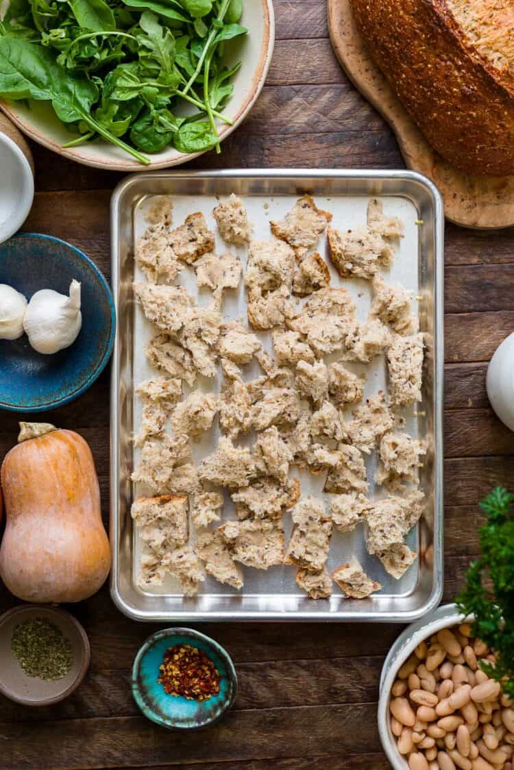 Chunks of bread on a sheet tray for a Ribollita (Tuscan-style Bread Soup) recipe.