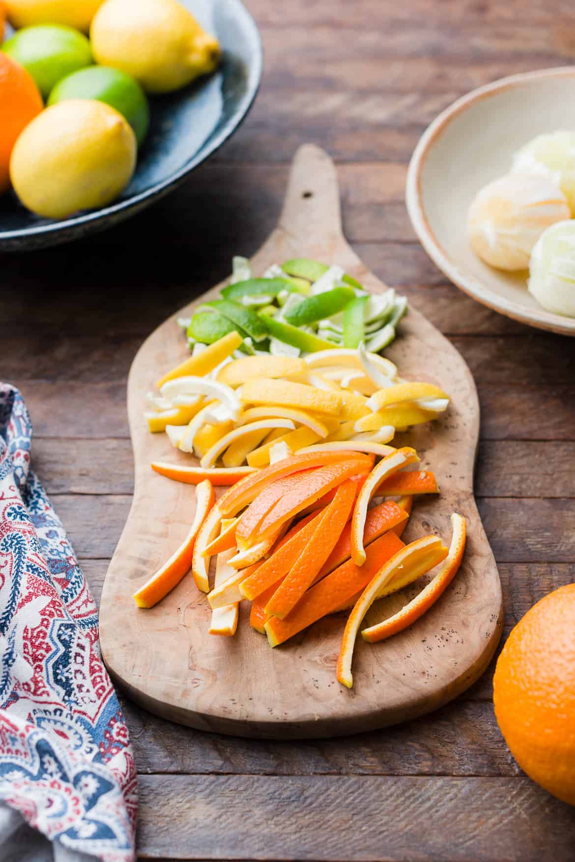 Orange, lemon, and lime peels, sliced on a cutting board.