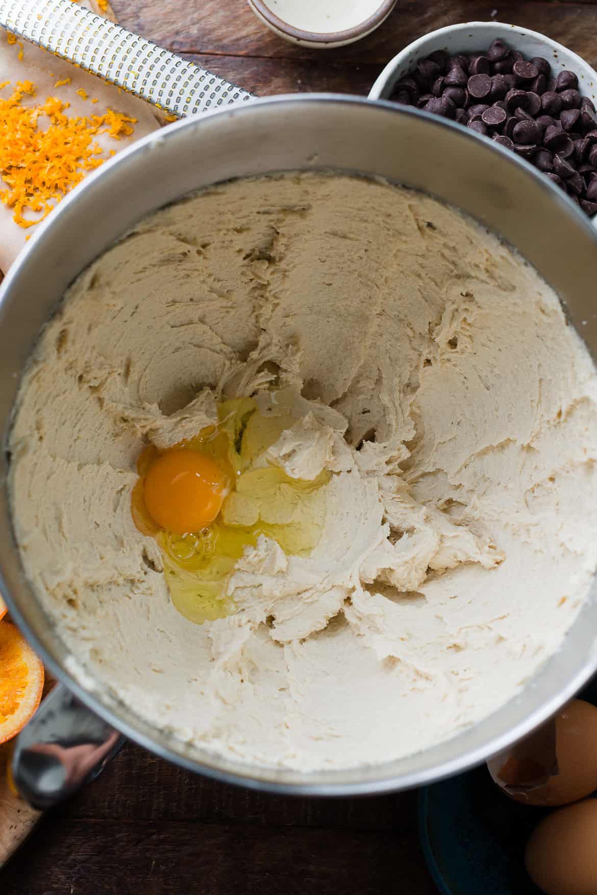 Adding eggs to cookie batter in a mixing bowl.