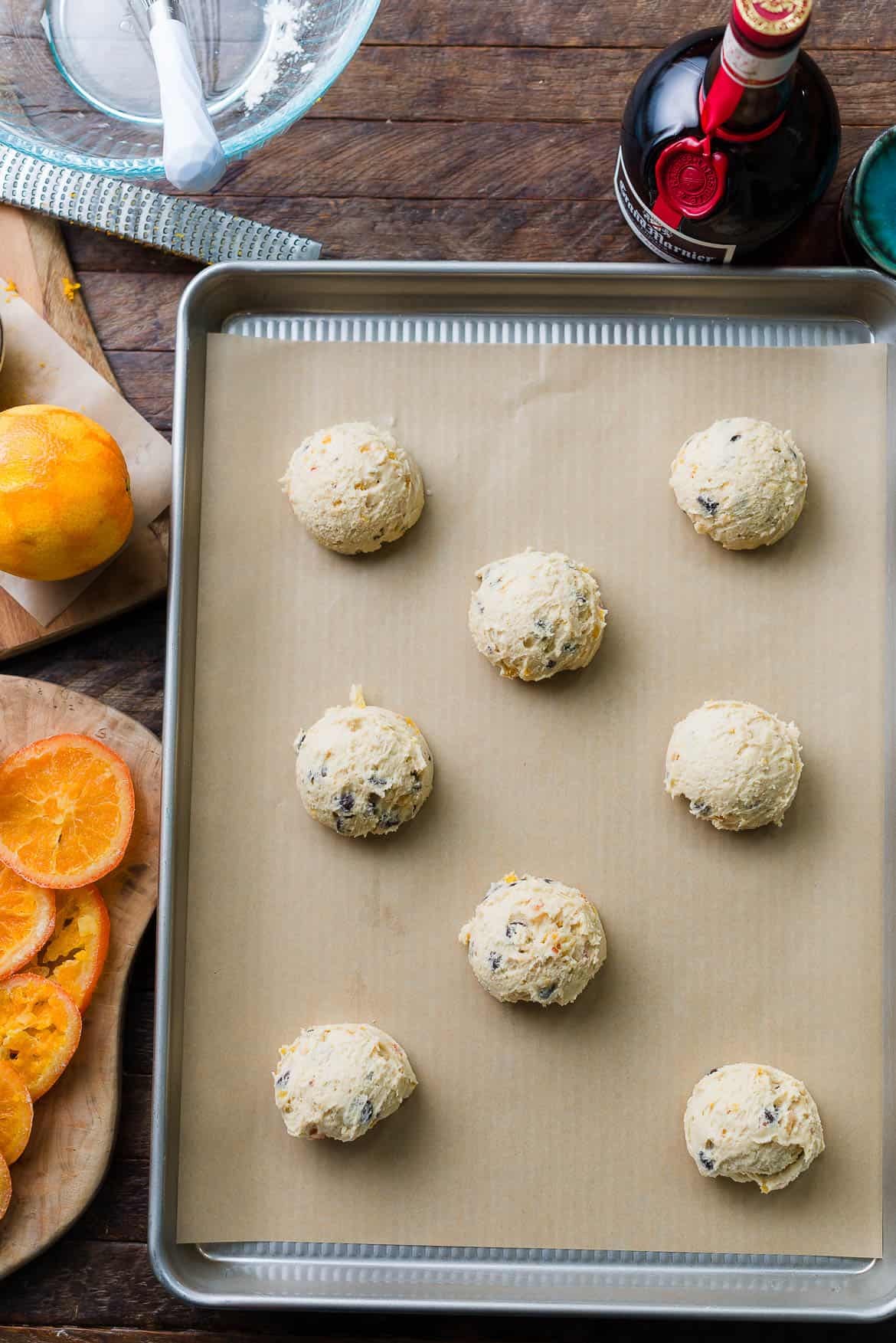 Scoops of Dark Chocolate Orange Cookies cookie dough on a cookie sheet.