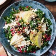 Kale and Quinoa Fall Salad with pears, pomegranates, feta, walnuts, dried cherries or cranberries, in a blue bowl.