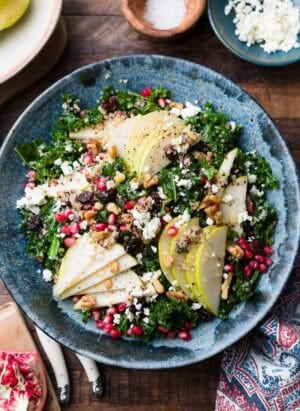 Kale and Quinoa Fall Salad with pears, pomegranates, feta, walnuts, dried cherries or cranberries, in a blue bowl.